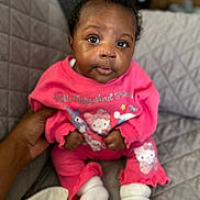 Sai is registered to the contest to win money with this photo: baby, child, infant, pink_clothing, hello_kitty, pajamas, socks, quilted_blanket, hand, indoor, person, cute, face, eyes, seated, cozy, soft_lighting, portrait, comfort, curious