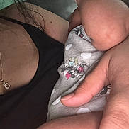 Nahomi is registered to the contest to win money with this photo: adult, arm, baby, black_top, care, cartoon, casual, closeup, clothing, couch, fabric, hand, holding, indoor, infant, intimate, necklace, person, polka_dot, skin