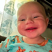 Olivia is registered to the contest to win money with this photo: baby, infant, child, smiling, face, portrait, close_up, indoor, pajamas, colorful_clothing, animal_pattern, teddy_bear, curtain, window, home, cozy, happy, sitting, camera, photograph