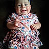 Olivia joined the competition — help win amazing prizes! baby, child, infant, smiling, happy, portrait, blue_bow, dress, floral_pattern, baseball, baseball_bat, sportswear, sitting, hands, face, eyes, indoor, dark_background, close_up, colorful_clothing