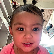 Emery joined the competition — help win amazing prizes! toddler, child, face, smiling, hair_buns, indoor, pink_clothing, necklace, person, cute, young_child, portrait, happy, head, shelf, curtains, window, furniture, home, baby