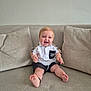 Cass joined the competition — help win amazing prizes! baby, child, smiling, sitting, couch, indoor, clothing, shorts, shirt, happy, cute, face, feet, pale_skin, blond_hair, blue_eyes, pillow, home, infant, portrait