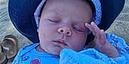 Colton is registered to the contest to win money with this photo: baby, sleeping, hat, blue_shirt, octopus_print, blanket, beach, sand, flip_flops, child, peaceful, outdoor, sun_hat, infant, close_up, portrait, resting, summer, vacation, cute