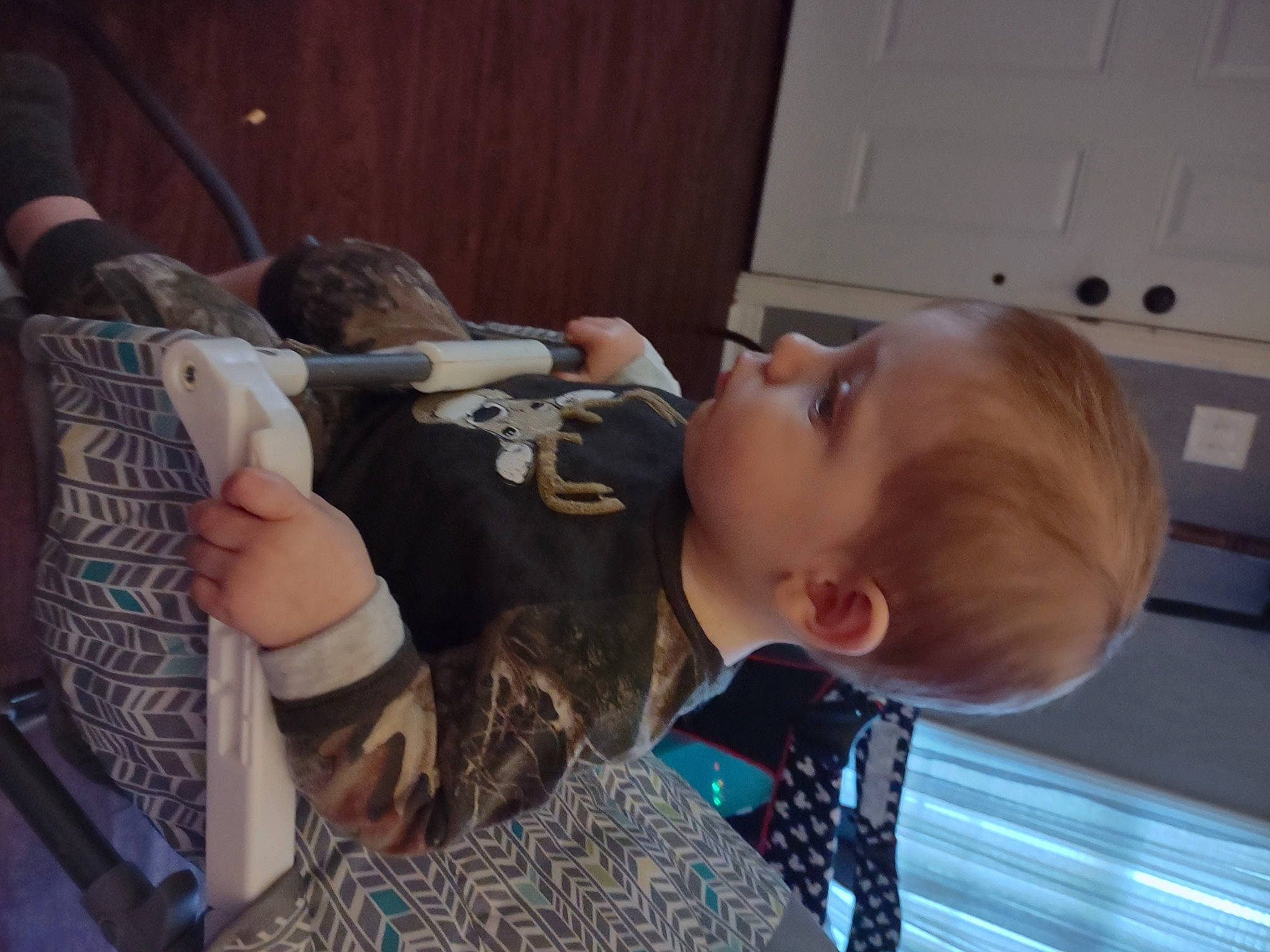 Noah is registered to the contest to win money with this photo: baby, child, comfort, ear, elbow, eye, finger, flooring, fun, glasses, human_body, microphone, person, play, room, sitting, suit, tattoo_artist, toddler, tree