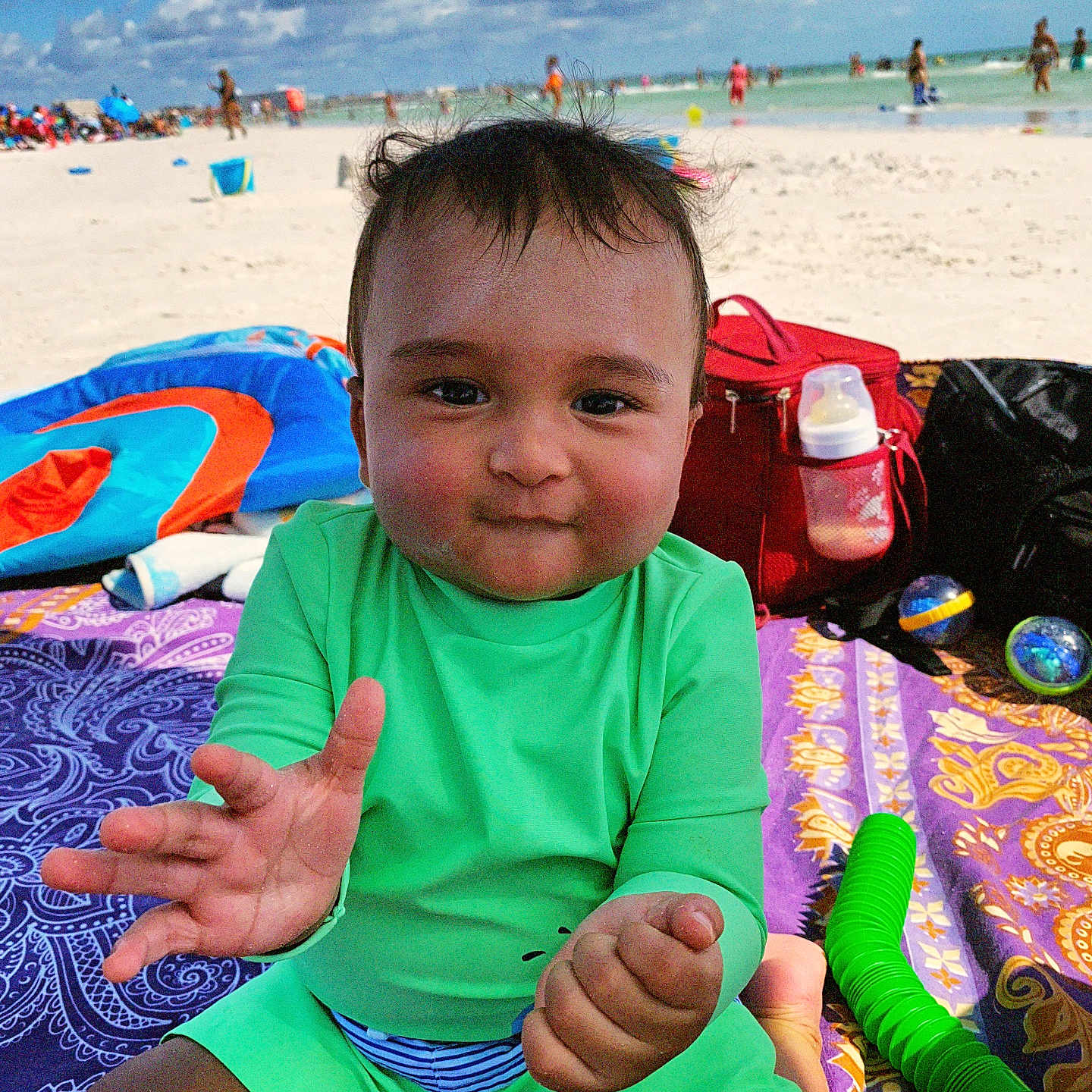 Jomar Keriel joined the competition — help win amazing prizes! baby, baby_bottle, beach, blanket, child, clouds, fun, green_clothing, ocean, outdoor, people, play, purple_blanket, red_bag, sand, smile, summer, sunny, toys, water