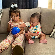 Jomar Keriel is registered to the contest to win money with this photo: child, baby, couch, balloon, bow, colorful_clothing, curtains, fabric, footwear, furniture, indoor, living_room, person, playful, sitting, smiling, toy, young_child, happy, family