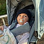 baby, pacifier, stroller, blanket, hat, child, outdoor, seated, clothing, infant, face, portrait, cute, young_child, baby_clothes, resting, baby_boy, baby_girl, closeup, daylight