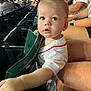 toddler, child, stadium, seating, sports_jersey, crowd, person, curious, mohawk, reaching_hand, spectator, event, casual_clothing, daylight, family, public_place, face, expression, indoor, people