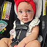 baby, car_seat, red_headband, straps, cute, child, infant, sitting, safety, wide_eyes, hand, foot, clothing, white_outfit, indoor, portrait, closeup, seatbelt, warning_label, curious