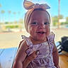 Maelynn joined the competition — help win amazing prizes! baby, child, smile, headband, bow, purple, dress, outdoor, sunlight, happy, person, portrait, infant, hand, skin, cute, young, seated, table, blurred_background
