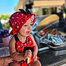 baby, child, smiling, hat, red, polka_dot, swimsuit, bow, watermelon, food, summer, happy, sitting, countertop, outdoor, person, cute, skin, headwear, daylight