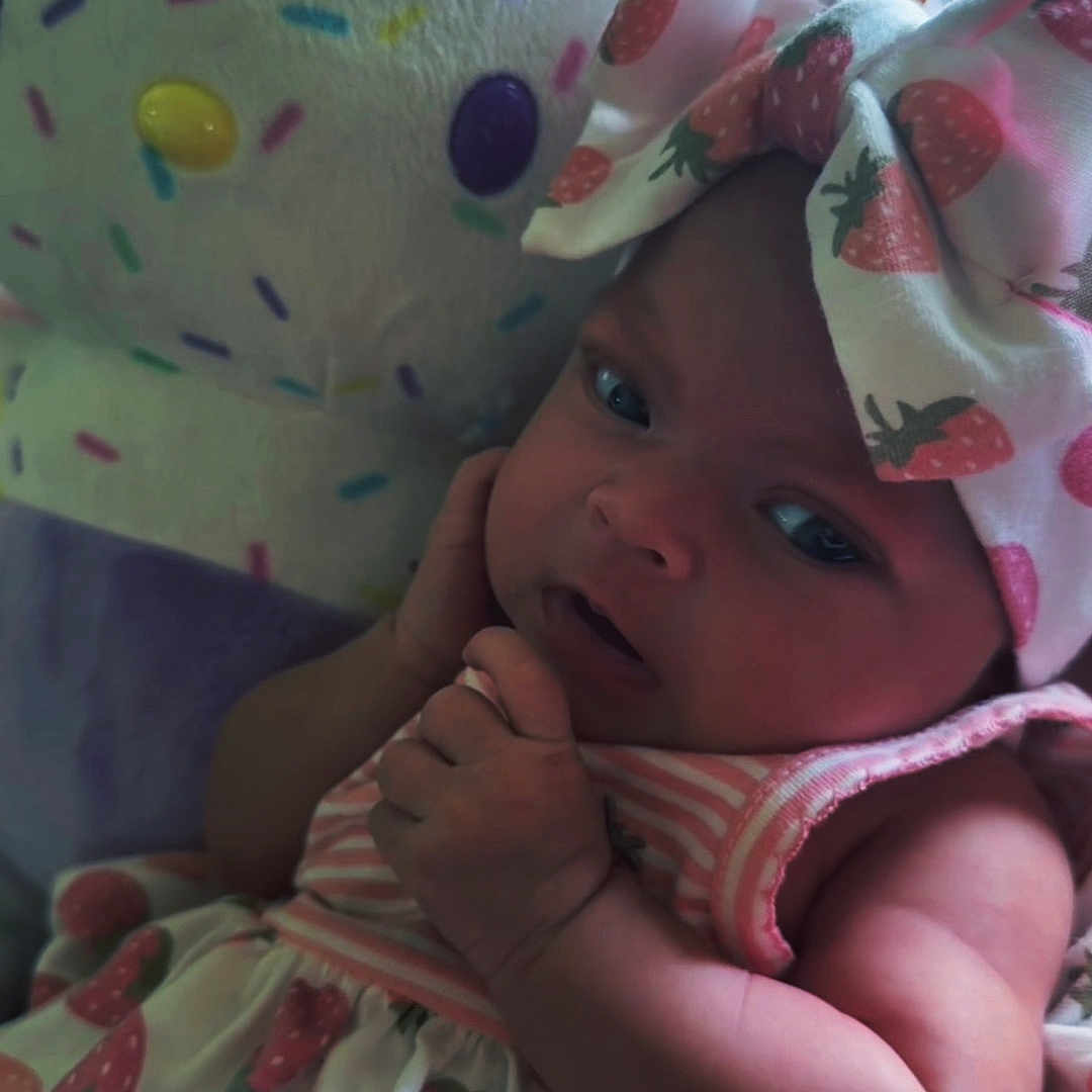 Ahzara Ourlanii joined the competition — help win amazing prizes! baby, infant, child, strawberry, headband, clothing, plush_toy, colorful, pattern, face, arm, hand, cute, indoors, portrait, soft_toy, pink, white, fabric, expression