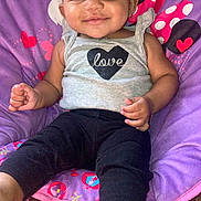 Armanie joined the competition — help win amazing prizes! baby, barefoot, black_bow, black_pants, carpet, child, colorful, cozy, cute, gray_tank_top, happy, headband, indoor, infant, love_heart, patterned, portrait, purple_chair, seated, smiling