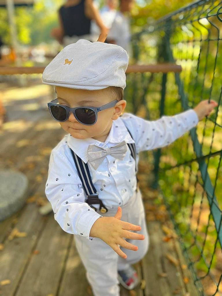 Rafaël a rejoint le concours — aidez-le/la à gagner de superbes lots ! baby_toddler_clothing, cap, child, dress_shirt, eyewear, fence, goggles, grass, happy, hat, headgear, leisure, person, plant, recreation, sun_hat, sunglasses, toddler, tree, vertebrate