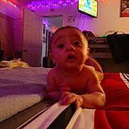 Raiden is registered to the contest to win money with this photo: baby, bed, blanket, child, clothing, curious, face, furniture, indoor, lighting, person, portrait, reaching, room, striped, television, toddler, toy, wall, young