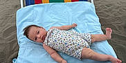 Inaya participe au concours pour gagner de l'argent avec cette photo : baby, infant, beach, sand, beach_chair, blue_cloth, floral_outfit, relaxing, lying_down, child, cute, person, summer, outdoor, skin, head, feet, arms, legs, hair