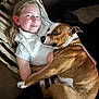 Urkan participe au concours pour gagner de l'argent avec cette photo : girl, dog, couch, pillow, smile, pet, indoor, relaxing, brown_dog, white_fur, child, affection, comfort, casual_clothing, gold_chain, light_hair, striped_pillow, resting, closeup, friendship