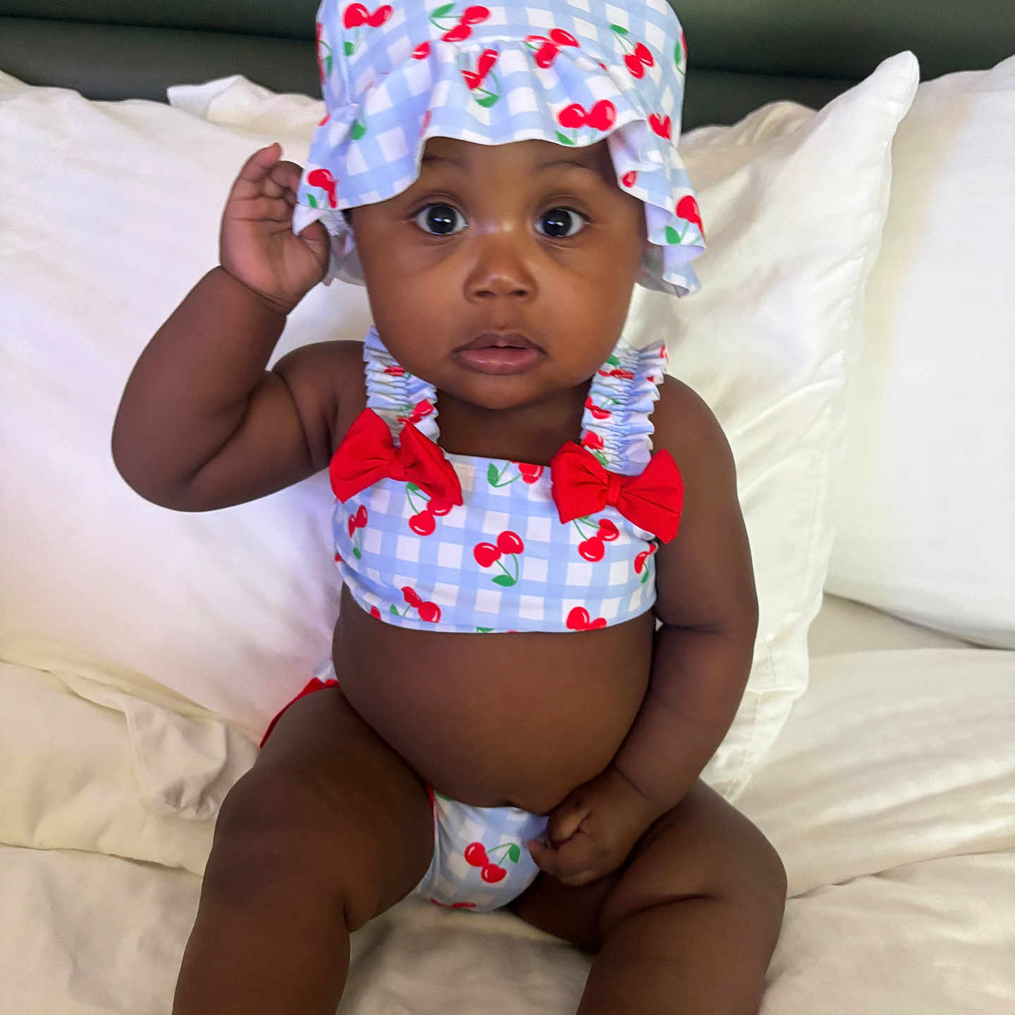 Brooklyn joined the competition — help win amazing prizes! baby, child, infant, hat, swimsuit, cherry_pattern, bed, pillow, white_bedding, cute, portrait, sitting, indoors, skin, expression, hand, summer_clothing, clothing, headwear, person