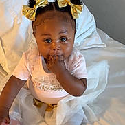Brooklyn joined the competition — help win amazing prizes! baby, child, infant, girl, gold_bows, curly_hair, pink_outfit, tutu, bed, white_bedding, sitting, fingers_in_mouth, cute, indoors, portrait, smiling, young_child, soft_lighting, cozy, happy