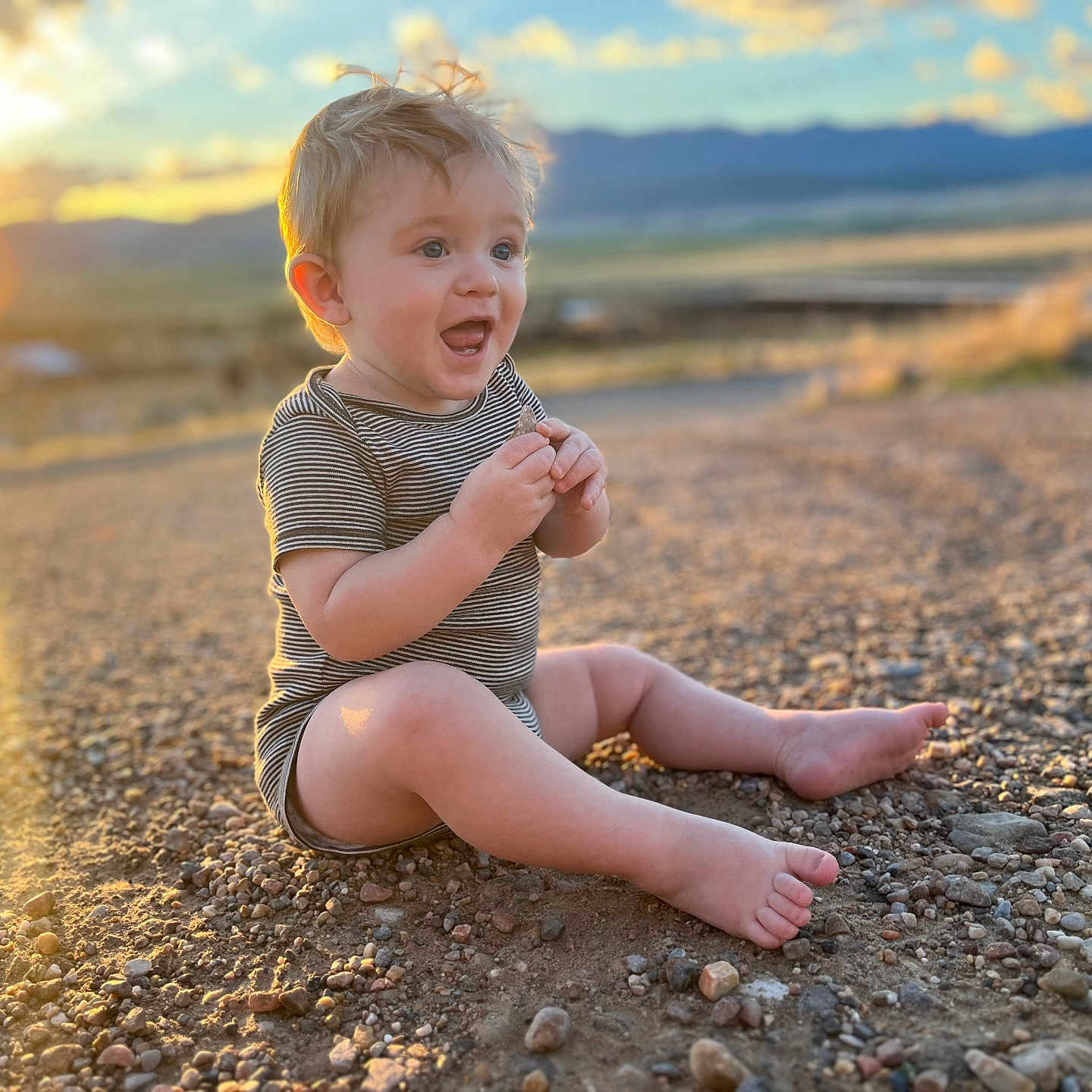 Rowen is registered to the contest to win money with this photo: bodypart, boy, child, clothing, face, finger, hand, happy, head, male, nature, outdoors, person, photography, portrait, rock, shorts, sitting, sky, soil