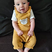 Lény participe au concours pour gagner de l'argent avec cette photo : baby, child, smiling, yellow_outfit, sitting, couch, indoor, happy, infant, cute, portrait, person, clothing, feet, hands, face, head, small_person, soft_texture, cozy