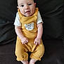 baby, child, smiling, yellow_outfit, sitting, couch, indoor, happy, infant, cute, portrait, person, clothing, feet, hands, face, head, small_person, soft_texture, cozy