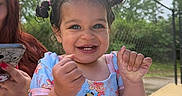 Aniyah is registered to the contest to win money with this photo: toddler, child, smiling, happy, outdoor, swimsuit, pigtails, fence, person, phone, summer, daylight, cute, portrait, nature, greenery, table, hand, playful, family