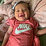 Mariana is registered to the contest to win money with this photo: baby, infant, smile, pink, nike, onesie, bow, blanket, soft, happy, cute, child, face, clothing, apparel, person, portrait, lying_down, indoors, cozy