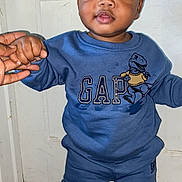Kyrin is registered to the contest to win money with this photo: toddler, child, blue_clothing, sweatshirt, pants, hand_holding, door, floor_mat, indoor, person, face, standing, curly_hair, socks, expression, casual_wear, home, support, young_child, cute