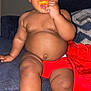 Kyrin joined the competition — help win amazing prizes! toddler, child, snack, couch, red_blanket, indoor, happy, sitting, face, hand, legs, bare_chest, food, cheese_puff, plush, cozy, cute, casual, home, relaxed