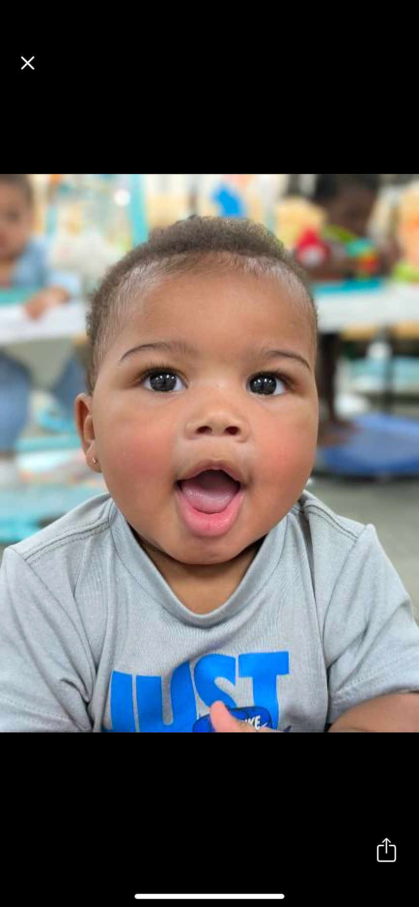 Kyrin joined the competition — help win amazing prizes! baby, child, face, expression, curious, indoor, play_area, shirt, gray_clothing, blue_text, close_up, portrait, cute, adorable, young_child, people, happy, open_mouth, skin, hair