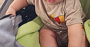 Kaidyn is registered to the contest to win money with this photo: baby, child, stroller, blanket, sock, clothing, winnie_the_pooh, curly_hair, indoors, infant, cute, looking_up, soft_toys, fabric, wood_floor, portrait, person, seated, expression, casual