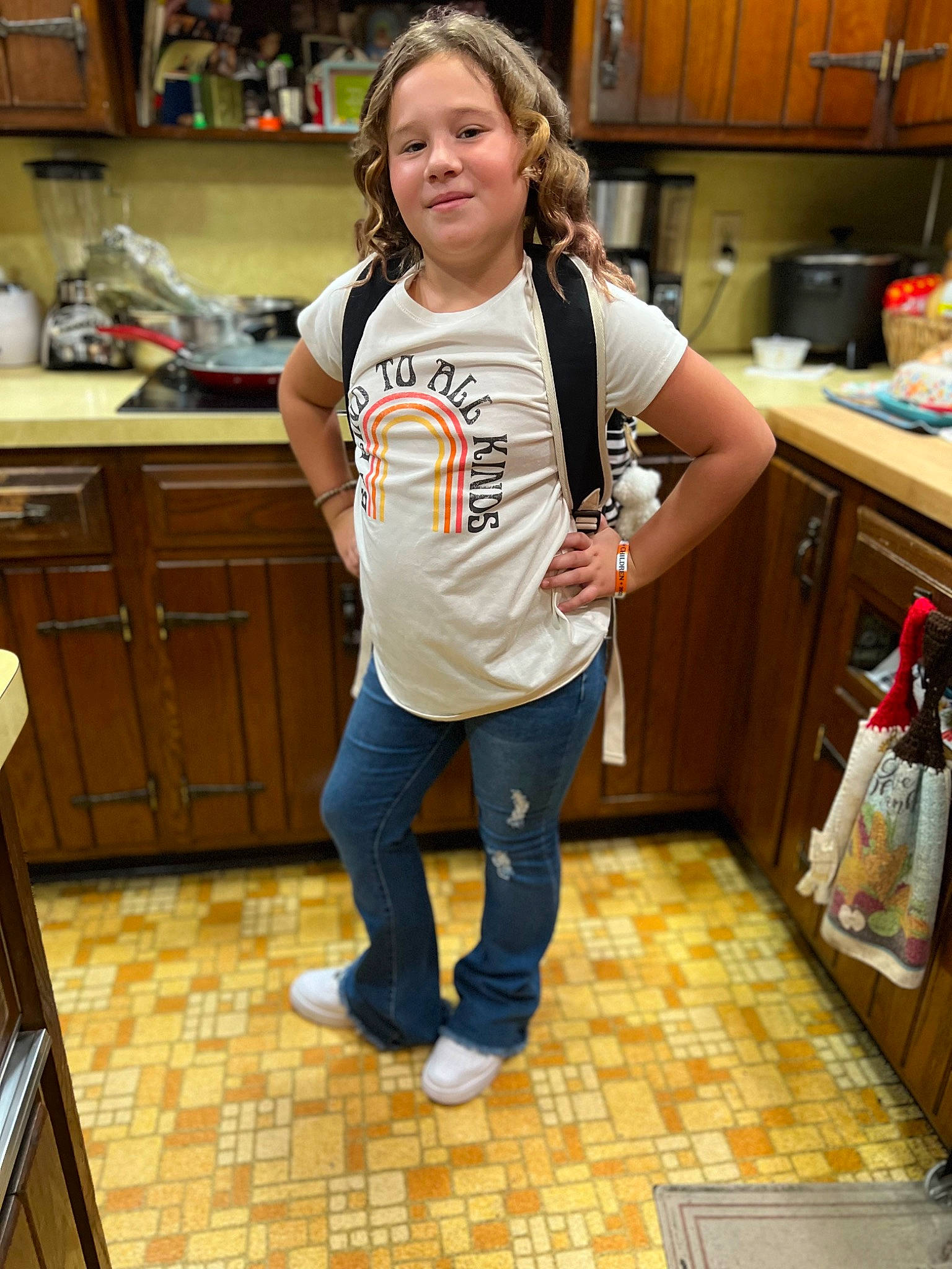 Sophia is registered to the contest to win money with this photo: blond, cabinetry, countertop, denim, floor, flooring, happy, hardwood, human_leg, joy, kitchen, kitchen_appliance, knee, person, sleeve, smile, sportswear, t_shirt, thigh, varnish