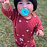 toddler, child, baby, outdoor, grass, standing, portrait, winter_clothing, hat, beanie, pom_pom, red_outfit, pacifier, blue_pacifier, raised_hand, pointing, brown_boots, smiling, face, cute