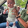 Paisley is registered to the contest to win money with this photo: baby, child, person, adult, hand, car_interior, seat, window, trees, clothing, shoes, socks, tattoo, watch, nail_polish, smile, holding, blanket, nature, casual