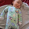 baby, infant, child, sleeping, face, portrait, onesie, pajamas, green_clothing, cartoon_print, beach_theme, blanket, cushion, bed, indoor, lying_down, cozy, cute, head, photograph