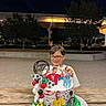 child, birthday, cake, soccer, football, portrait, smiling, glasses, outdoor, night, celebration, sports_fan, soccer_ball, balloons, candles, table, wooden_table, stadium, trees, birthday_message