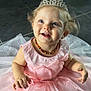 child, toddler, princess, tiara, pink_dress, smiling, happy, blue_eyes, curly_hair, necklace, floor, tiles, indoor, portrait, cute, baby, sitting, dress, celebration, joyful