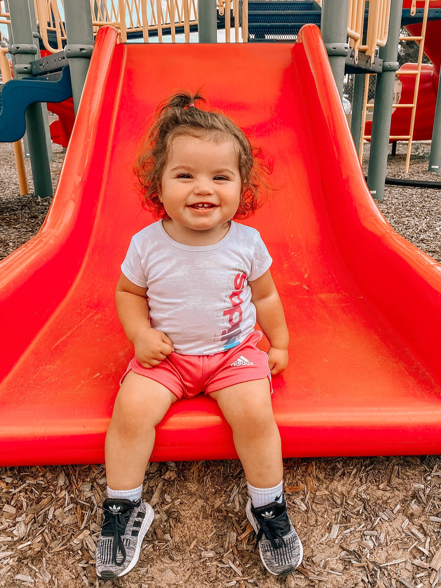 Laynee is registered to the contest to win money with this photo: baby_toddler_clothing, beauty, child, chute, city, facial_expression, fun, grass, green, happy, joy, leisure, person, pink, playground, playground_slide, product, recreation, red, smile