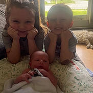 Buckley is registered to the contest to win money with this photo: baby, blanket, child, children, cushion, cute, dog, family, floor, happy, home, indoor, natural_light, pajamas, person, portrait, resting, sibling, smiling, window