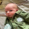 Buckley is registered to the contest to win money with this photo: baby, blanket, buttoned_shirt, child, closeup, clothing, cute, explorer_label, eyes, face, green_shirt, indoor, infant, lying_down, newborn, patterned_mitten, portrait, skin, soft_lighting, young_child