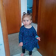 Luna joined the competition — help win amazing prizes! toddler, child, girl, blue_dress, pigtails, barefoot, indoor, doorway, carpet, tile_floor, toilet_paper, curious, standing, black_leggings, hair_ties, home, room, wooden_door, expression, young_child