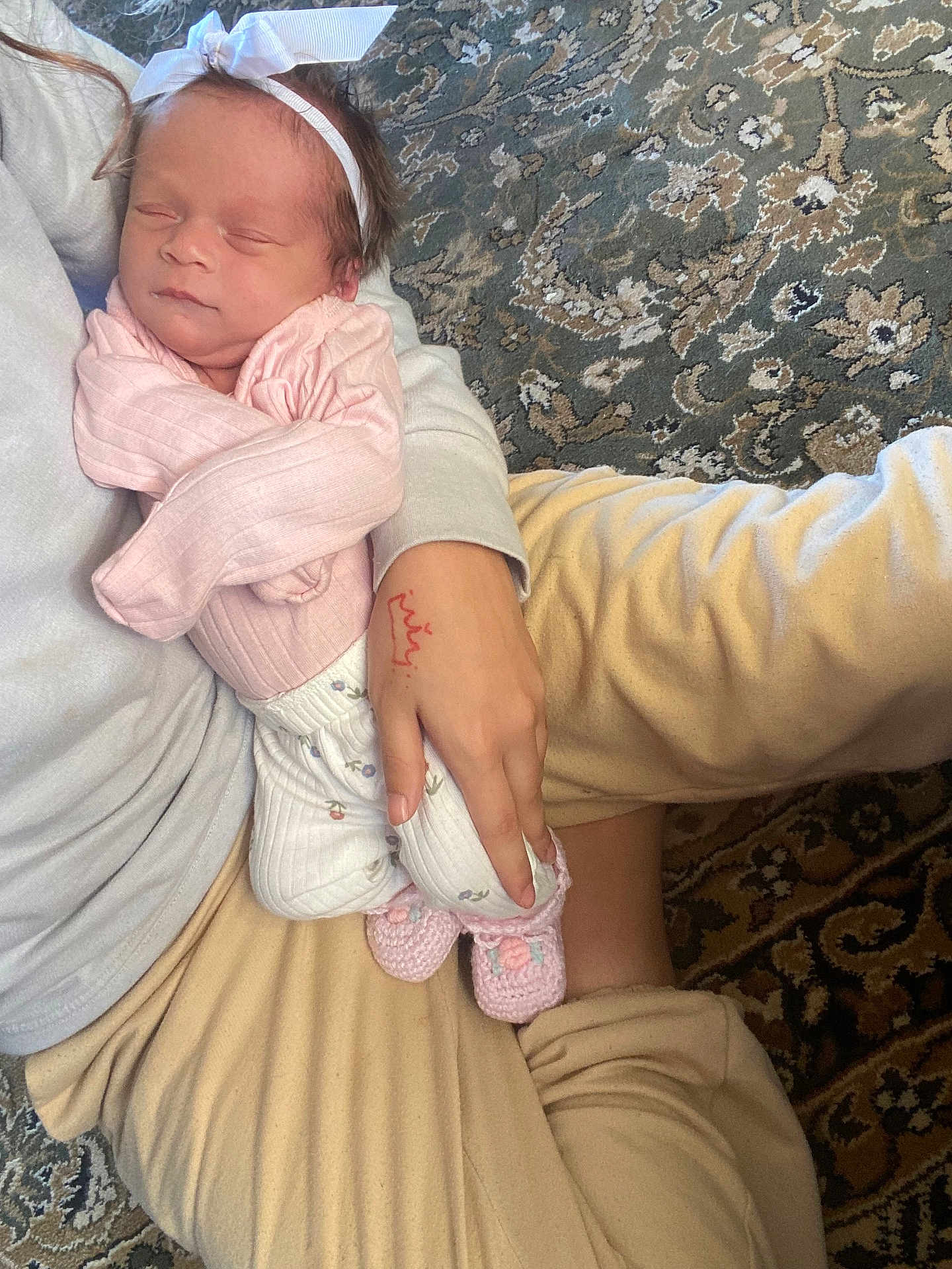 Ariyah joined the competition — help win amazing prizes! newborn, baby, infant, sleeping, headband, pink_clothing, hand, adult, carpet, floor, patterned, cozy, soft_lighting, legs, sitting, comfort, home, indoor, person, peaceful
