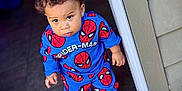 Karmelo is registered to the contest to win money with this photo: toddler, child, boy, standing, doorway, blue_clothing, spiderman_outfit, curly_hair, white_shoes, wooden_deck, house_siding, indoors, outdoors, portrait, looking_up, casual, cute, young_child, fashion, expression