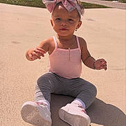 Ilaria is registered to the contest to win money with this photo: child, toddler, pink_bow, tank_top, leggings, white_shoes, outdoor, concrete, sunlight, shadow, necklace, bracelet, earrings, cute, baby, sitting, curious, daytime, casual_clothing, portrait