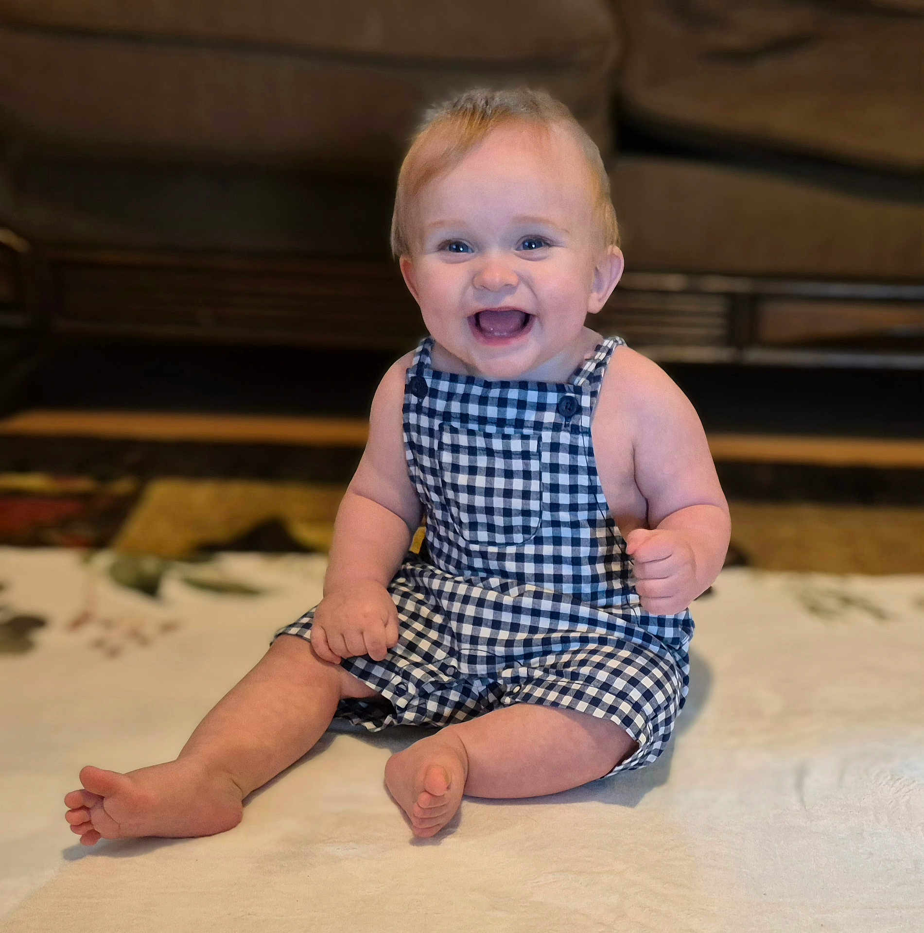 Rowan joined the competition — help win amazing prizes! baby, child, smiling, sitting, romper, blue_checkered_clothing, barefoot, indoor, blanket, happy, face, person, cute, infant, home, furniture, carpet, young, portrait, cheerful