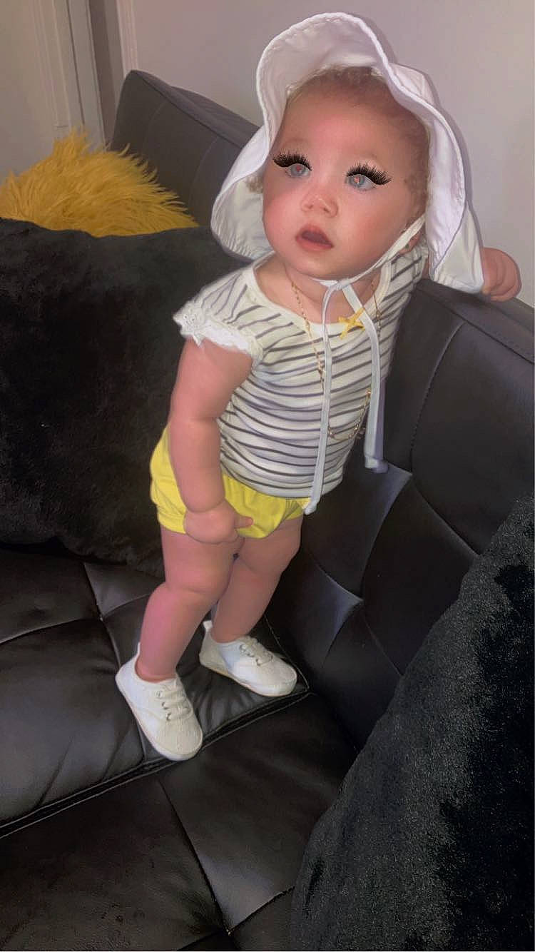 Liberty is registered to the contest to win money with this photo: baby, baby_toddler_clothing, car_seat, chair, cheek, child, comfort, couch, face, fun, head, headwear, human_leg, knee, lap, person, room, seat_belt, sitting, sock