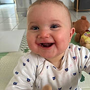 Charly participe au concours pour gagner de l'argent avec cette photo : baby, smiling, face, indoor, child, onesie, cute, happy, toddler, toy, teddy_bear, floor, patterned_clothing, closeup, infant, person, expression, bright_eyes, candid, playful
