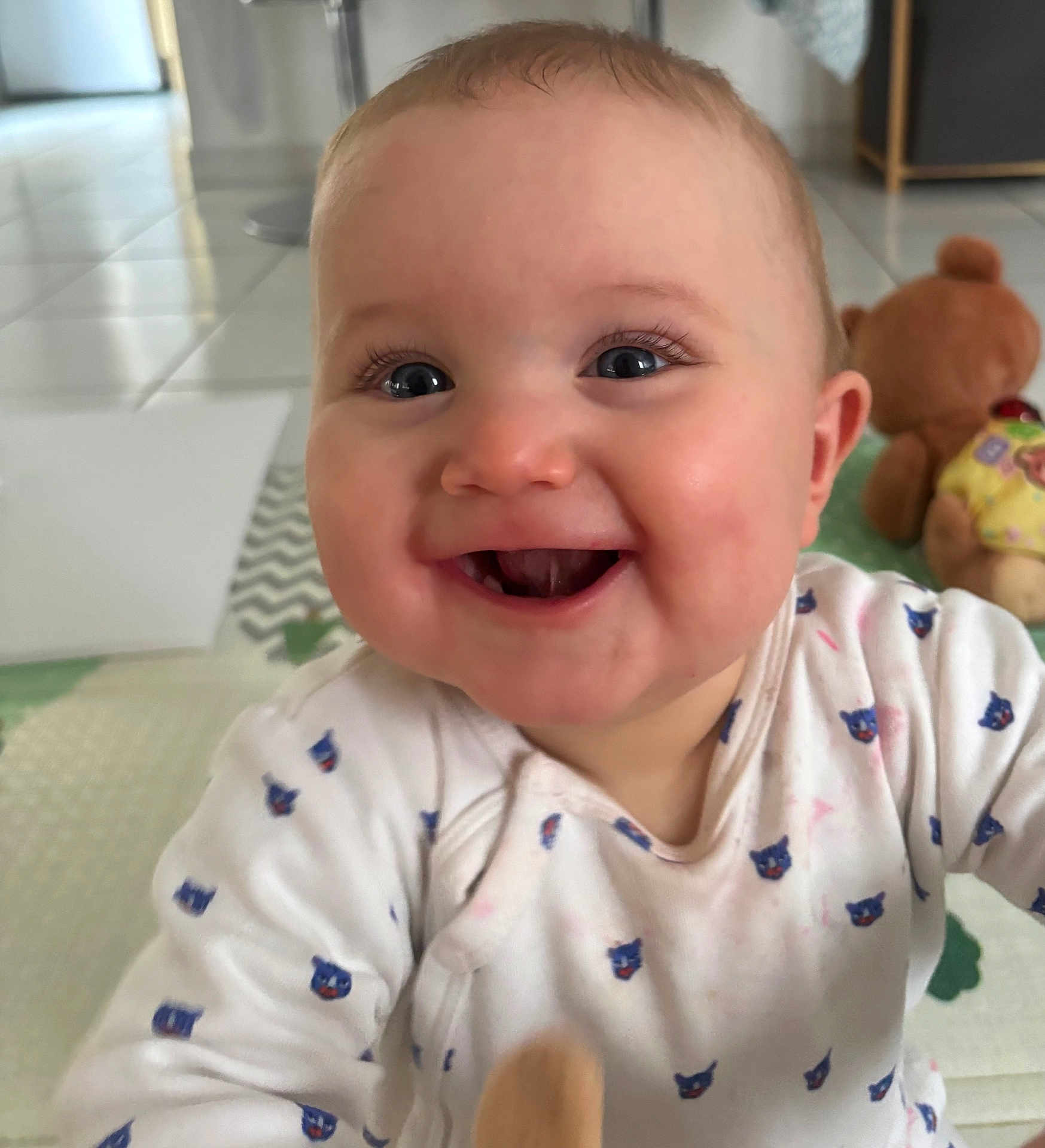 Charly participe au concours pour gagner de l'argent avec cette photo : baby, smiling, face, indoor, child, onesie, cute, happy, toddler, toy, teddy_bear, floor, patterned_clothing, closeup, infant, person, expression, bright_eyes, candid, playful