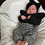 baby, sleeping, infant, black_top, ruffles, checkered_pants, pink_shoes, headband, bow, blanket, soft, comfortable, resting, cute, child, fashion, portrait, indoors, cozy, clothing